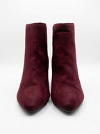 Pair of burgundy suede ankle boots on a white background